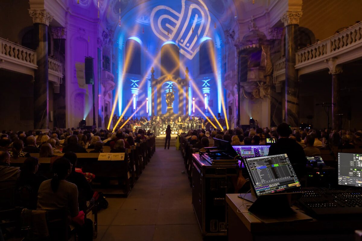 View from the mixing desk across the packed Friedenskirche Ludwigsburg: beams of light over the stage and a glowing heart on the vault