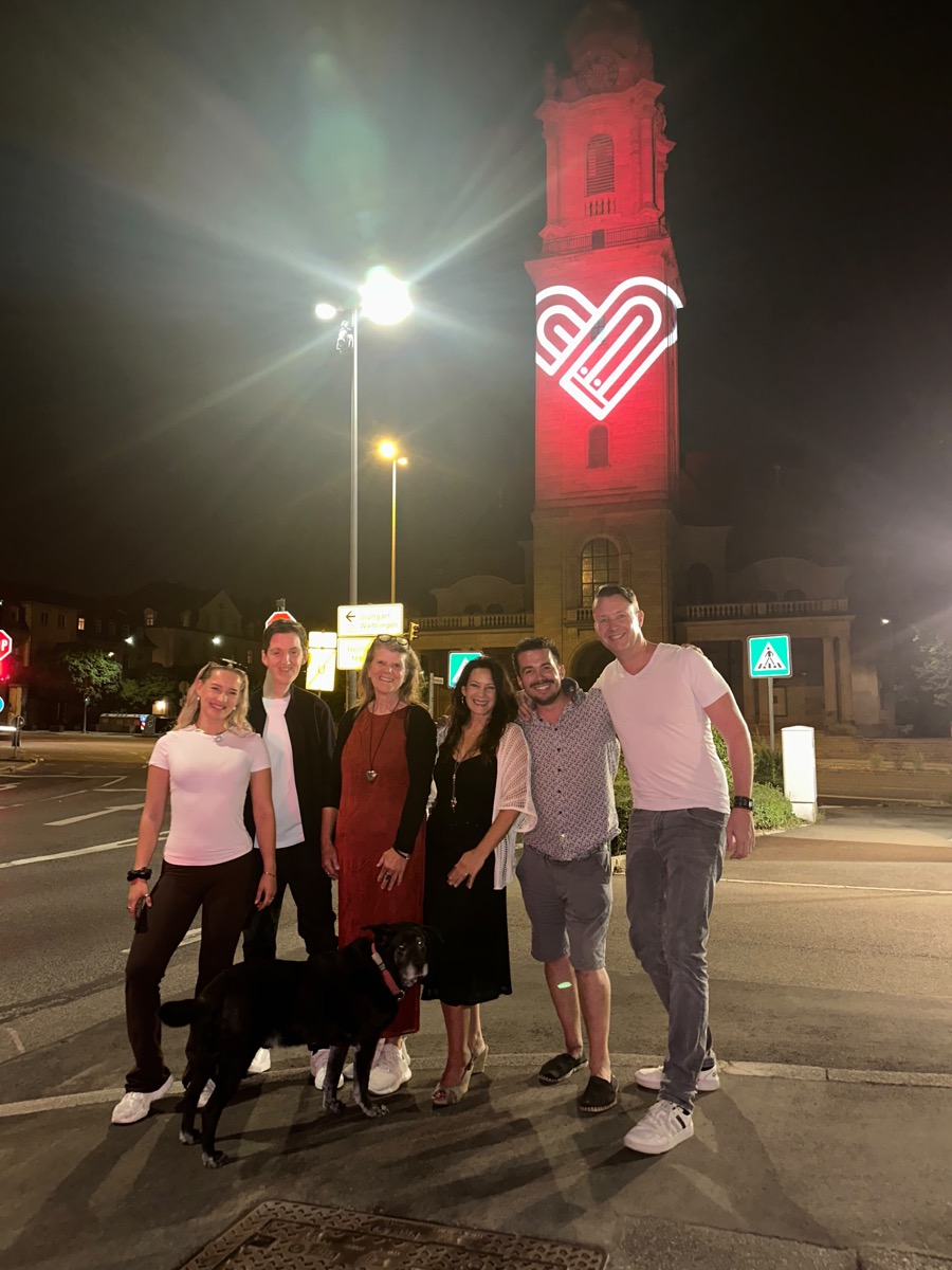 Petra, Jessie, Gudrun, Dirk, Christian und Patrick mit Hund Dobby vor der beleuchteten Friedenskirche